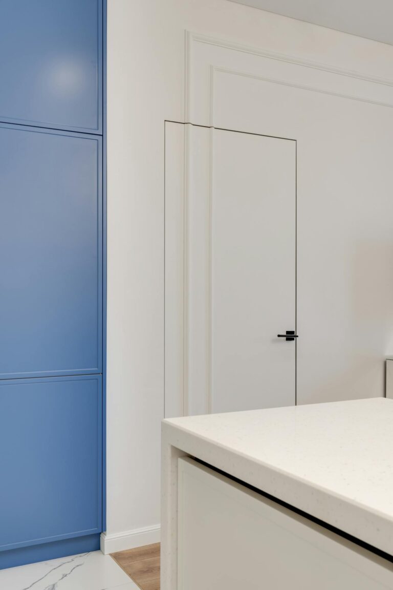 Modern kitchen interior featuring a sleek blue wardrobe and clean white surfaces.